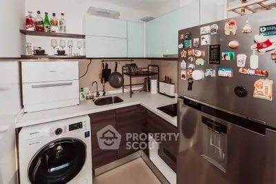 Modern kitchen with sleek appliances and compact design, featuring a washing machine and stylish fridge.