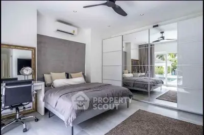 Modern bedroom with mirrored wardrobe and pool view, featuring sleek design and neutral tones.