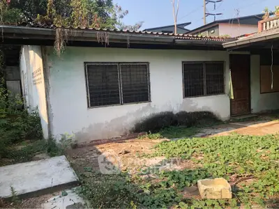 Charming fixer-upper with potential, featuring a rustic exterior and lush greenery, ideal for renovation enthusiasts.