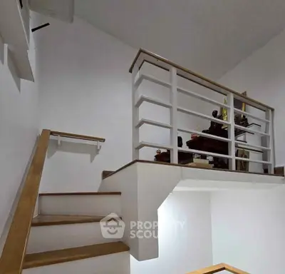 Modern staircase with wooden handrails and decorative sculptures on landing.