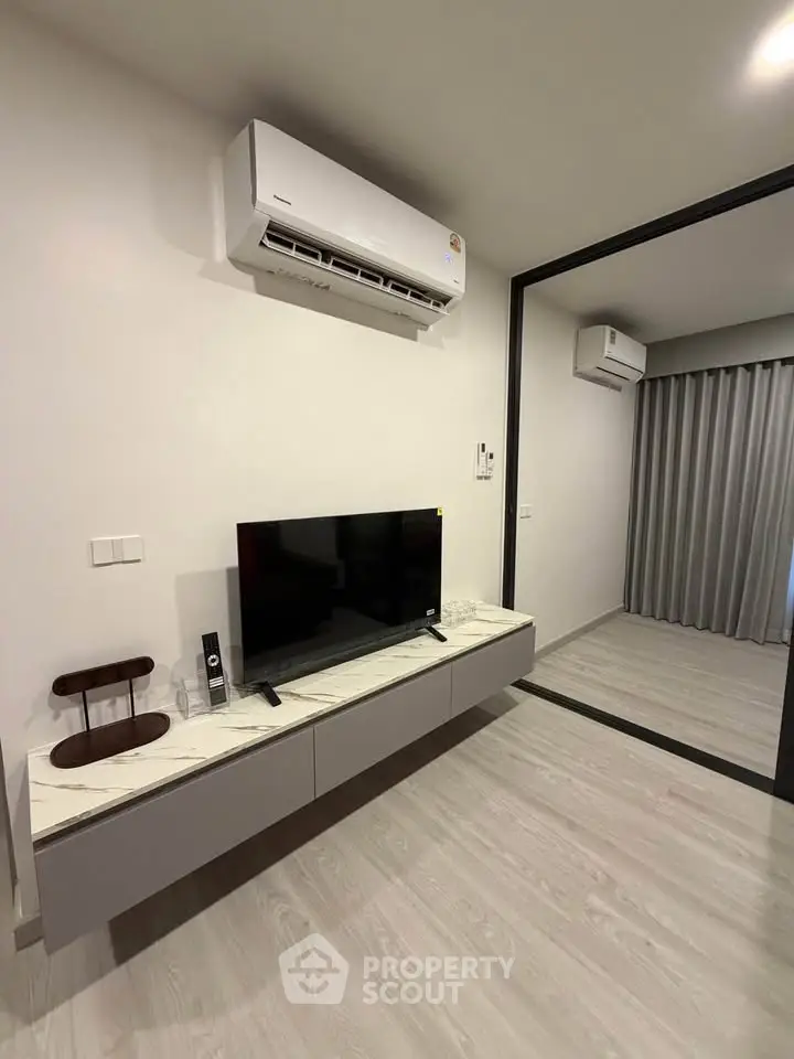 Modern living room with sleek TV setup and air conditioning in a stylish apartment.