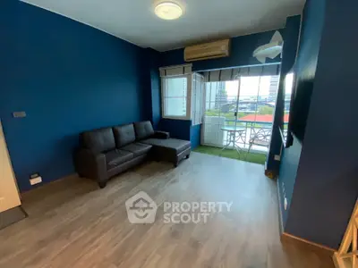 Modern living room with blue walls, dark sofa, and balcony view