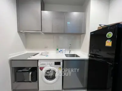Modern kitchen with washing machine and black fridge in compact layout