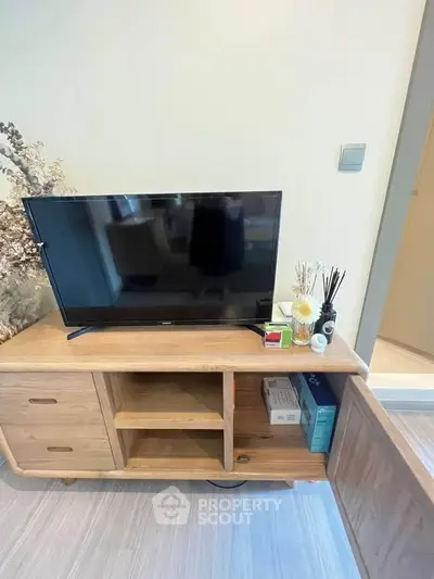 Modern living room with wooden TV stand and decorative items, showcasing a cozy and stylish interior.