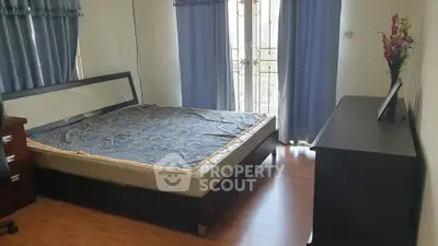 Spacious bedroom with large windows and elegant decor in modern apartment.