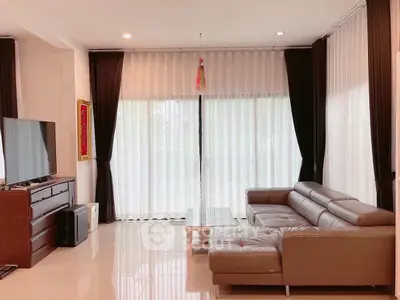 Spacious living room with modern leather sofa and large TV, perfect for relaxation.