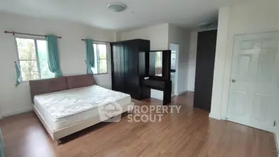 Spacious bedroom with wooden flooring and large windows for natural light