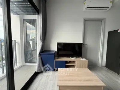 Modern living room with balcony view, featuring sleek furniture and air conditioning.