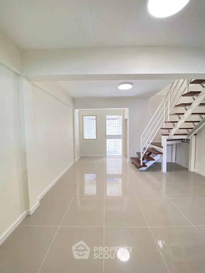 Spacious modern living room with sleek staircase and glossy tiled floors