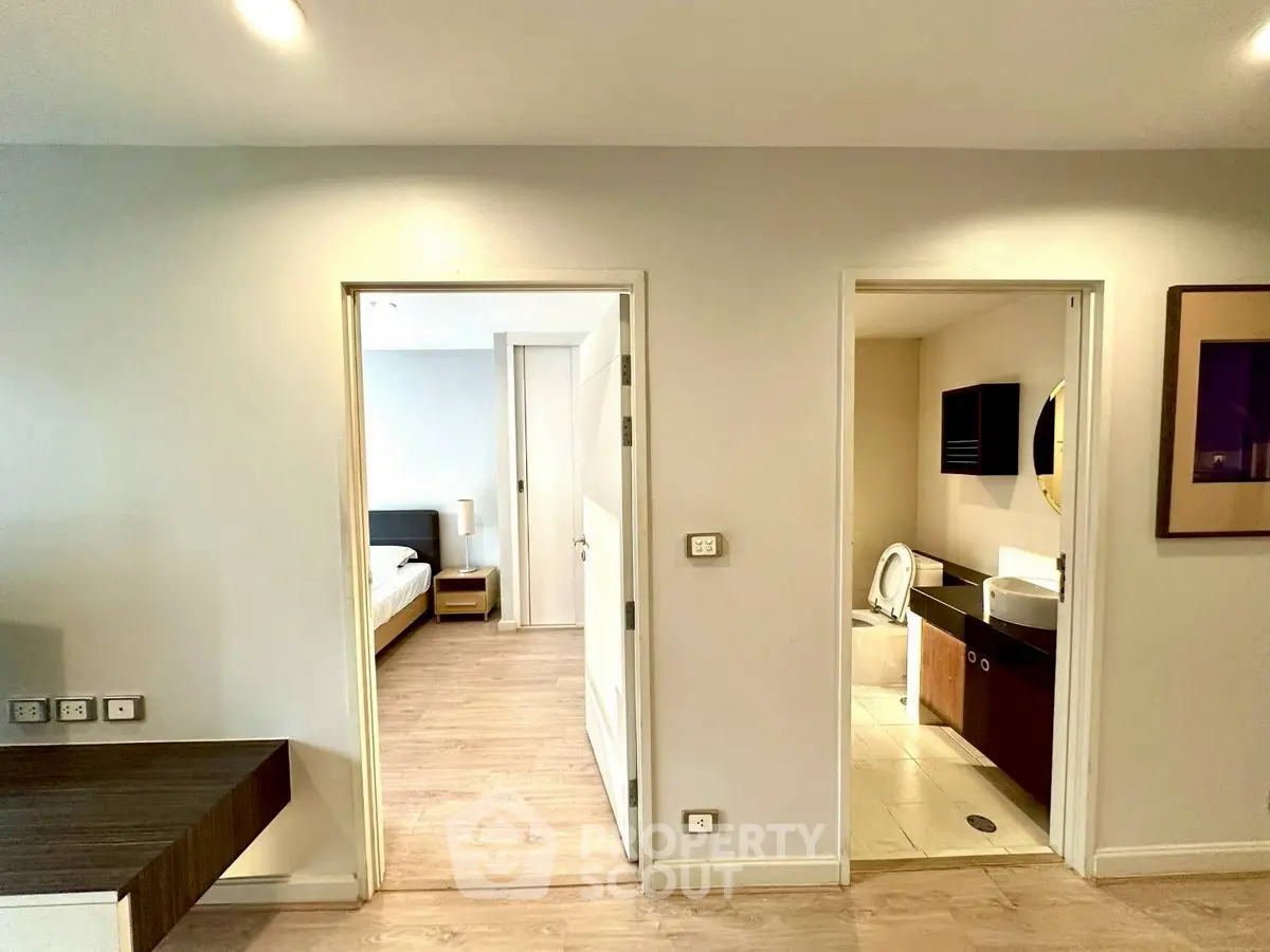 Modern apartment interior with bedroom and bathroom view, showcasing sleek design and bright lighting.
