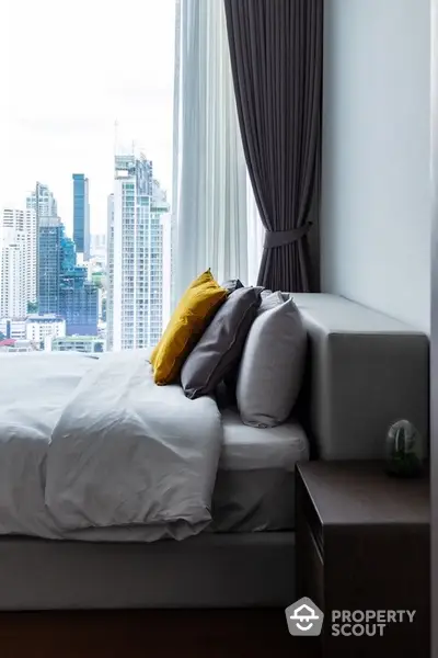 Luxurious bedroom with city view and modern decor in high-rise apartment.