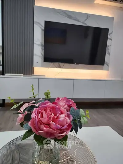 Modern living room with sleek TV setup and elegant floral centerpiece.