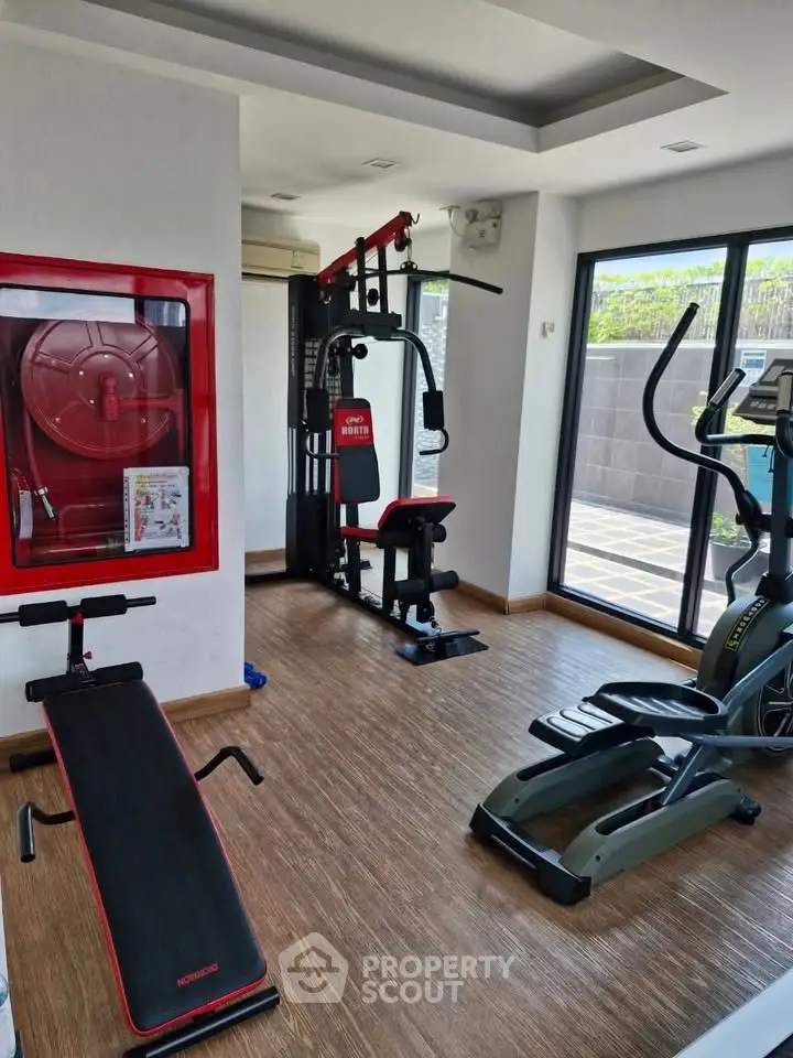 Modern gym with exercise equipment and large windows in a residential building.