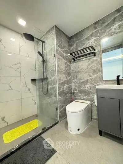 Modern bathroom with sleek marble tiles and glass shower enclosure