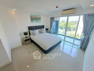Spacious bedroom with large windows and modern decor, offering a serene view and abundant natural light.