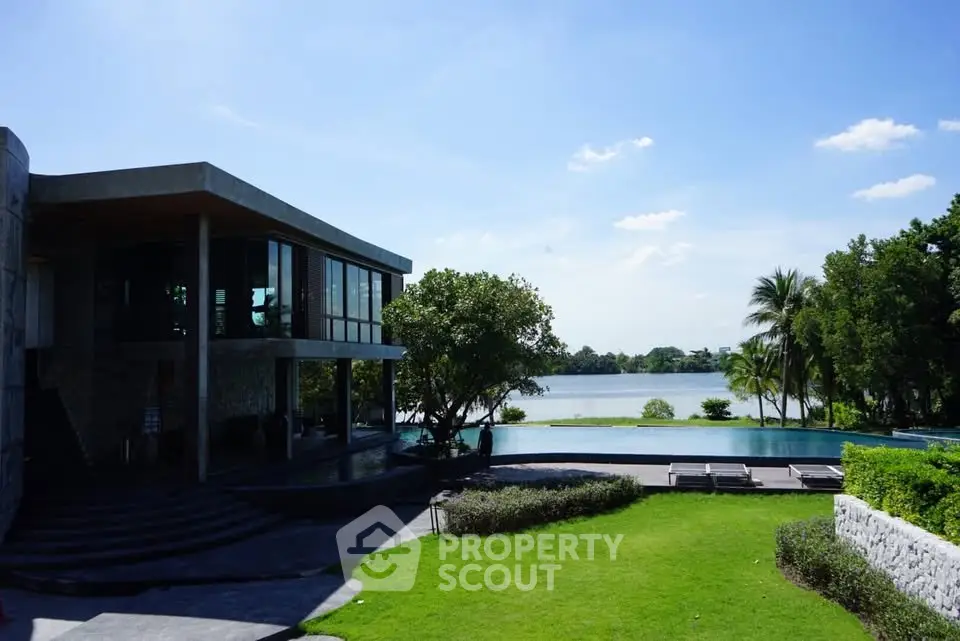 Luxurious lakeside property with modern architecture and lush green lawn, offering serene water views.