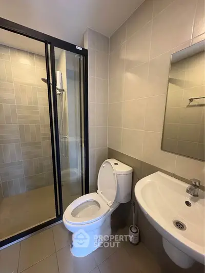 Modern bathroom with glass shower and sleek fixtures in contemporary apartment.