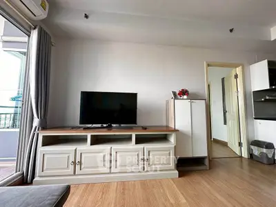 Modern living room with TV and balcony access, featuring stylish wooden flooring and elegant decor.