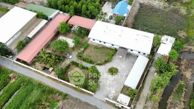 Aerial view of a spacious property with multiple buildings and lush greenery, ideal for development or investment.