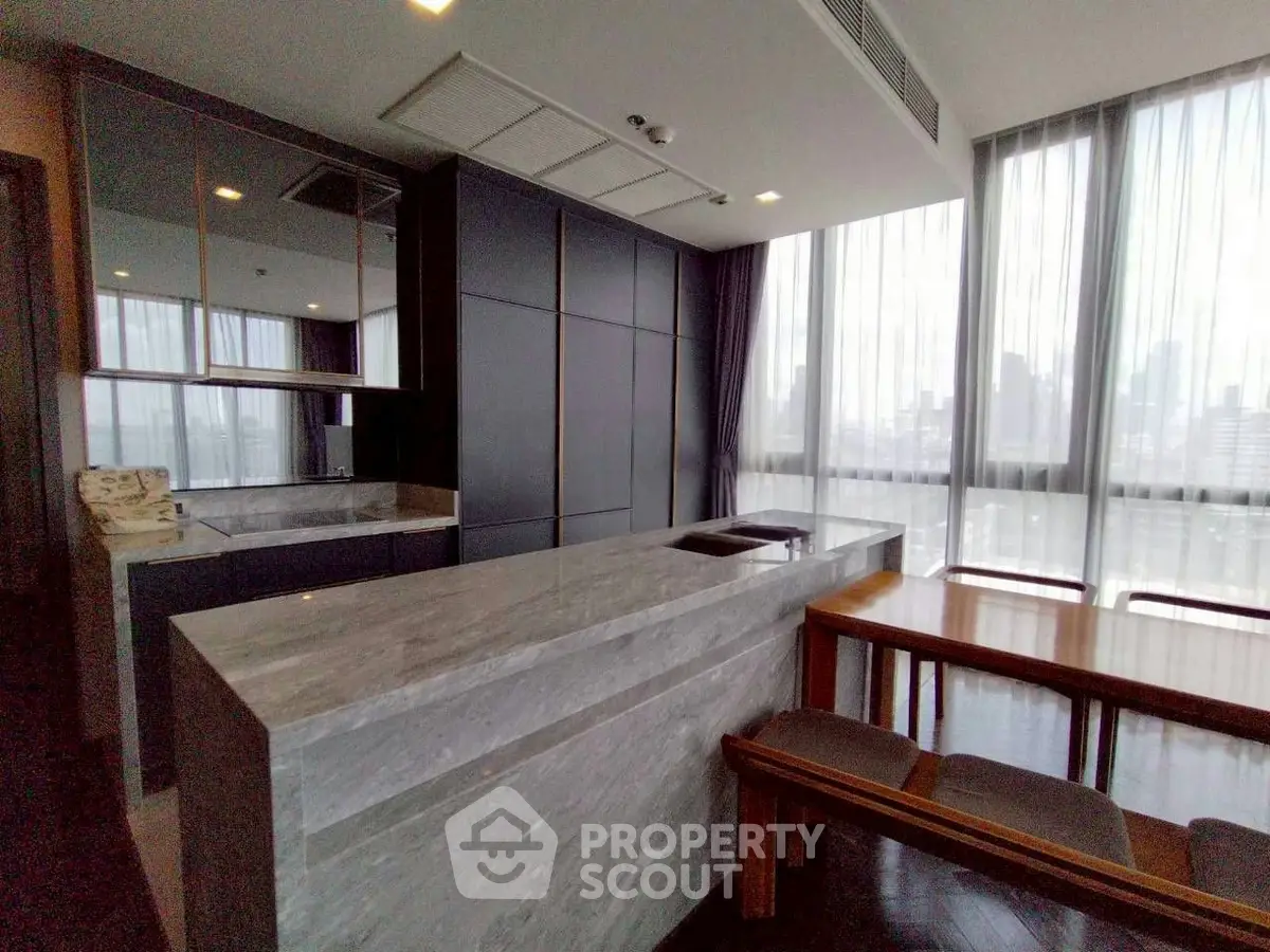 Modern kitchen with sleek design and open layout, featuring a stylish island and dining area with city views.