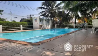 Stunning outdoor pool area with lush greenery and palm trees, perfect for relaxation and leisure.