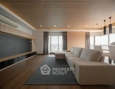 Spacious modern living room with elegant wooden flooring and large windows offering natural light.