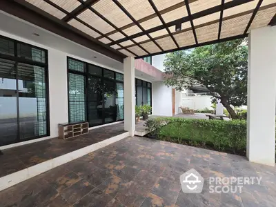 Modern home entrance with spacious patio and lush greenery