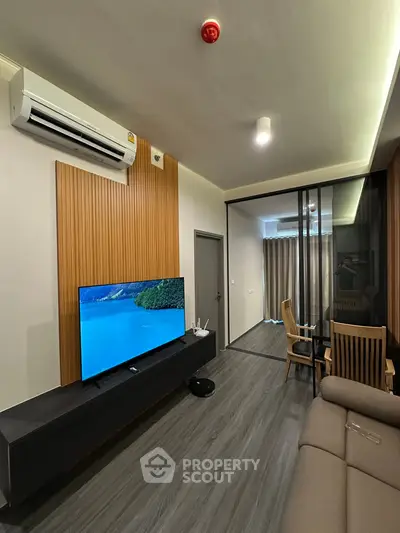 Modern living room with sleek design, featuring a large TV, air conditioning, and stylish furniture.