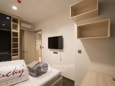 Modern bedroom with built-in storage and wall-mounted TV in a cozy apartment.