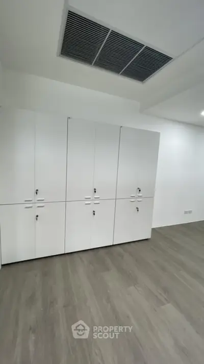 Spacious room with sleek white storage cabinets and modern flooring, ideal for versatile use.