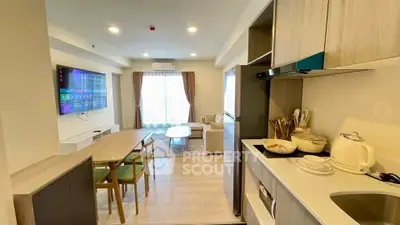 Modern open-layout living room and kitchen with stylish furniture and natural light.