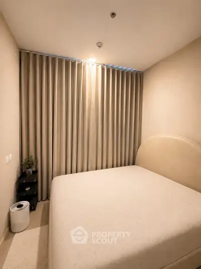 Cozy bedroom with elegant curtains and modern decor, perfect for relaxation.