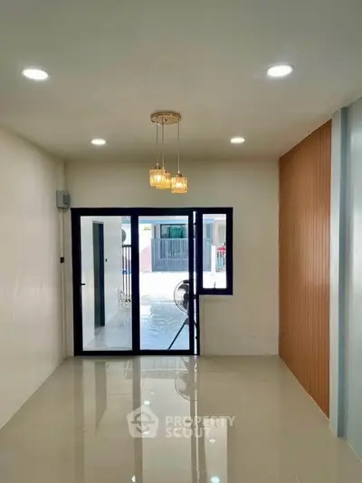 Modern living room with sleek lighting and large glass doors leading to balcony.