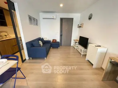 Modern living room with blue sofa, TV, and wooden flooring in cozy apartment.