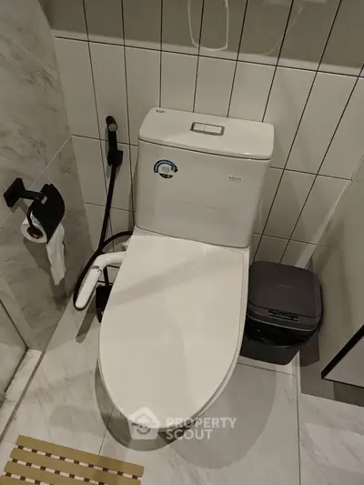 Modern bathroom with sleek toilet and marble tiles, showcasing contemporary design and functionality.