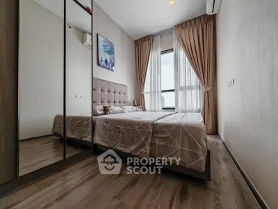 Modern bedroom with mirrored wardrobe and large window offering natural light.