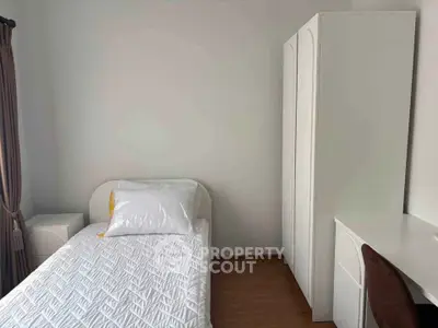 Cozy bedroom with single bed, wardrobe, and natural light from window.