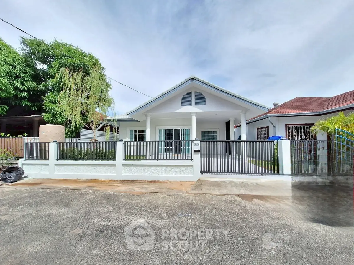 Charming single-story house with a gated front yard and lush greenery.