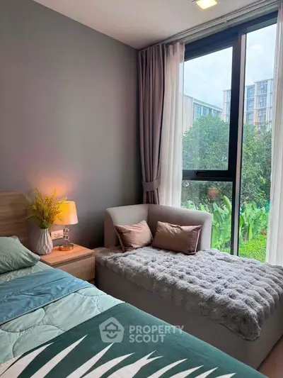 Cozy bedroom with large window and garden view, featuring stylish decor and comfortable seating area.