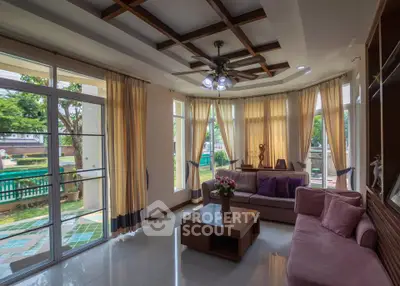 Spacious living room with large windows and garden view, featuring cozy seating and elegant decor.