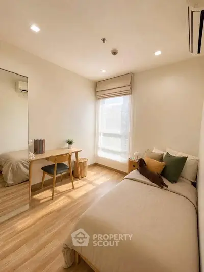 Cozy bedroom with natural light, wooden flooring, and minimalist decor for a serene living experience.