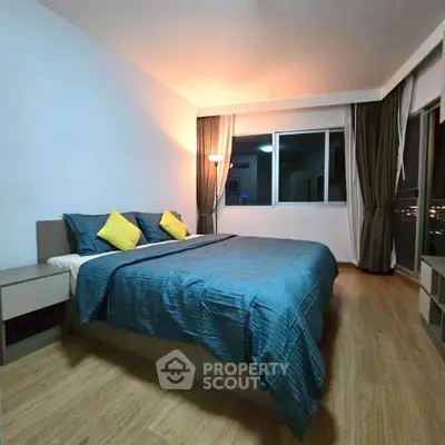 Spacious bedroom with modern decor and large window offering city views.