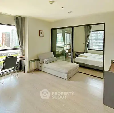 Modern studio apartment with city view, featuring a cozy bed, sleek desk, and large windows for natural light.