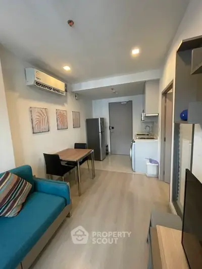 Modern living room with open kitchen, featuring stylish decor and cozy seating.