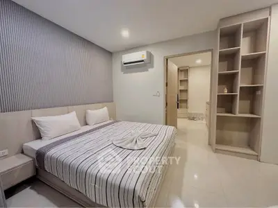 Modern bedroom with stylish decor and built-in storage, featuring a comfortable bed and air conditioning.