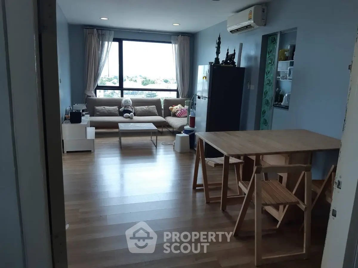 Spacious living room with modern decor and large window offering natural light and scenic views.