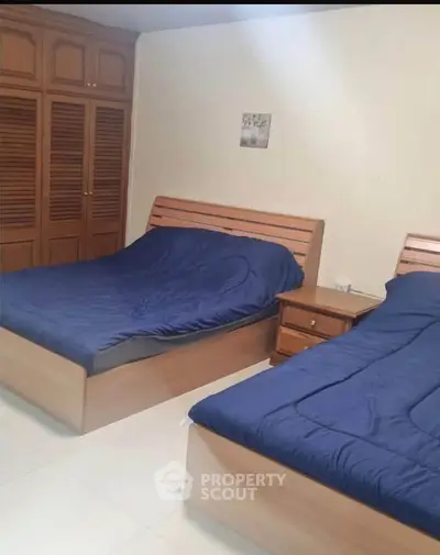 Spacious bedroom with twin beds and wooden wardrobe, perfect for comfortable living.
