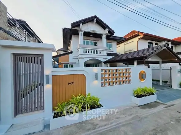Charming two-story house with modern facade and gated entrance in a serene neighborhood.
