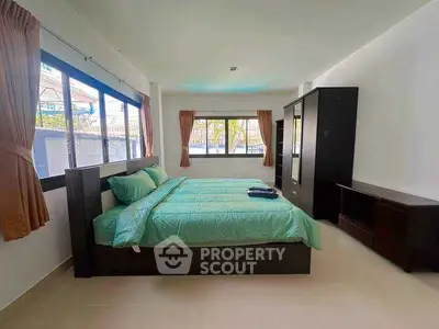 Spacious bedroom with large windows and modern furniture, perfect for comfort and relaxation.