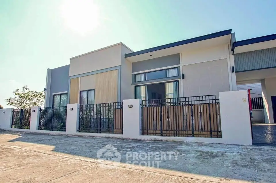 Modern single-story house with sleek design and spacious driveway in sunny neighborhood.